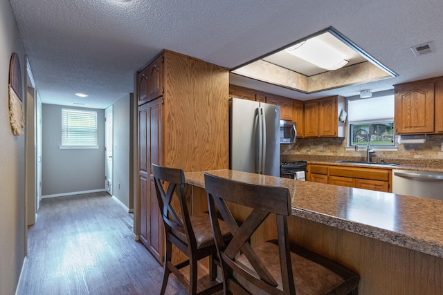 kitchen with tasteful backsplash, sink, dark hardwood / wood-style flooring, appliances with stainless steel finishes, and a textured ceiling