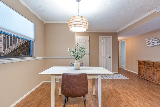 dining area featuring hardwood / wood-style flooring, ornamental molding, and a textured ceiling