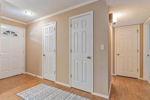 foyer entrance featuring ornamental molding, light wood-type flooring, and a textured ceiling