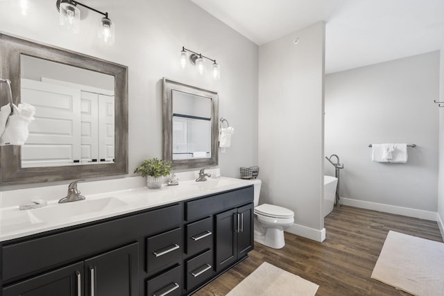 bathroom with toilet, vanity, a bath, and wood-type flooring