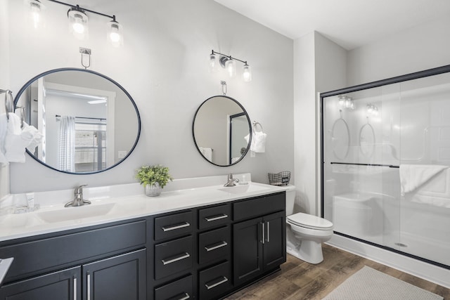 bathroom featuring a shower with shower door, vanity, and toilet