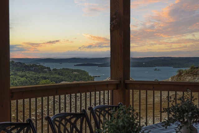 deck at dusk featuring a water view