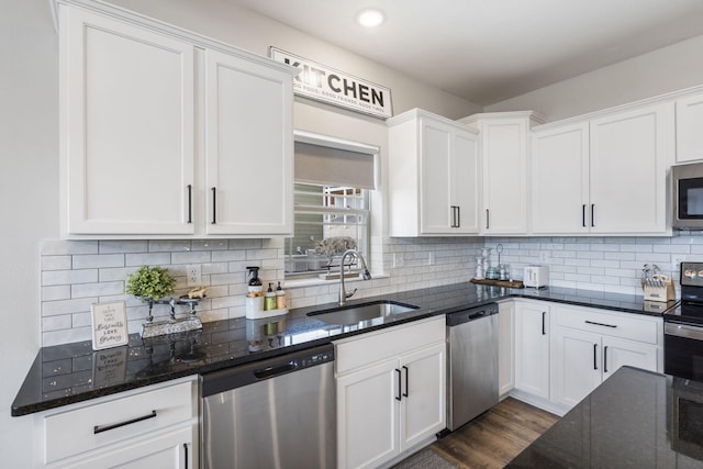 kitchen featuring dark stone countertops, white cabinets, stainless steel appliances, and sink