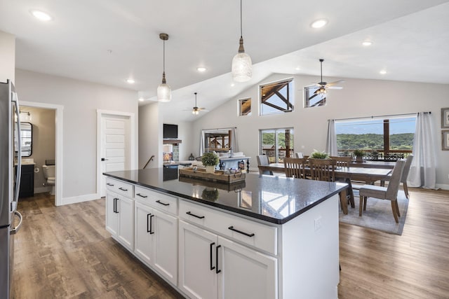 kitchen with ceiling fan, a center island, white cabinets, dark wood-type flooring, and decorative light fixtures