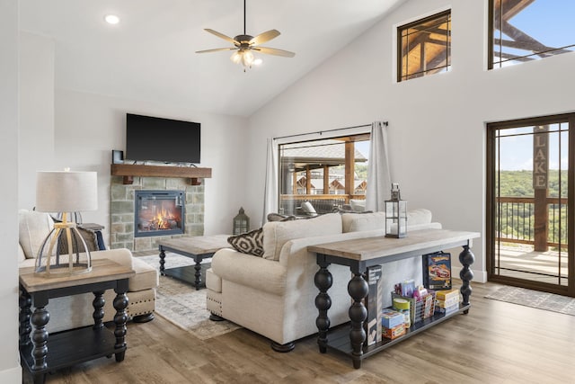 living room with high vaulted ceiling, ceiling fan, a fireplace, and wood-type flooring