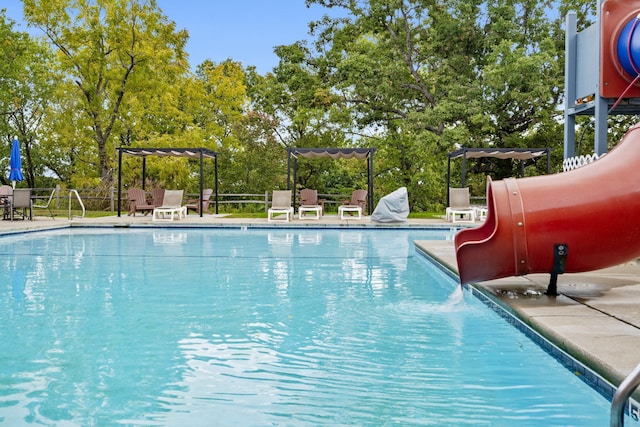 view of swimming pool featuring a patio, a pergola, and a water slide