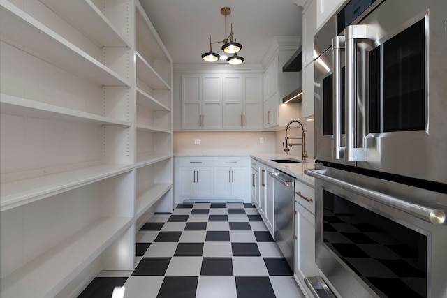 kitchen featuring decorative light fixtures, appliances with stainless steel finishes, sink, and white cabinetry