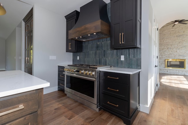 kitchen with high end range, decorative backsplash, dark wood-type flooring, and custom exhaust hood