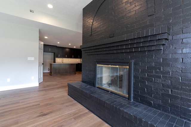 unfurnished living room featuring a brick fireplace, brick wall, and hardwood / wood-style floors