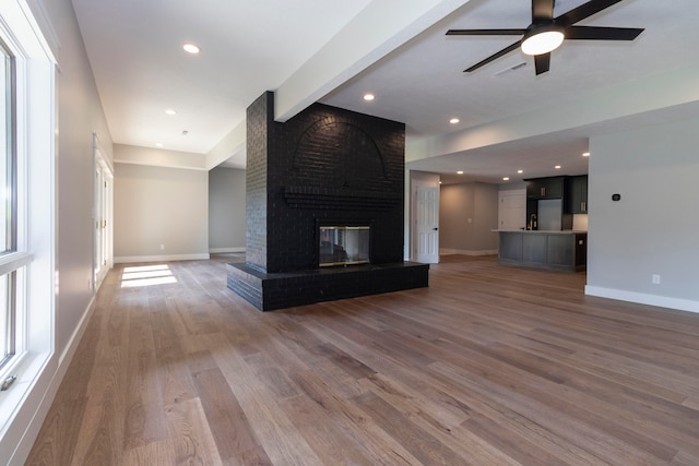 unfurnished living room with a brick fireplace, dark wood-type flooring, and ceiling fan