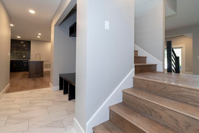 stairway featuring hardwood / wood-style floors and sink