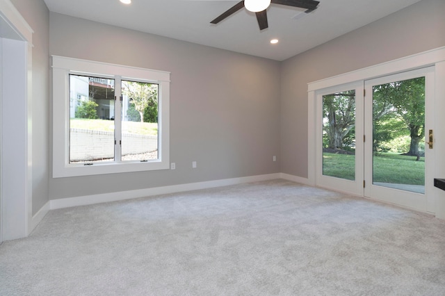 empty room with light carpet, ceiling fan, and a wealth of natural light