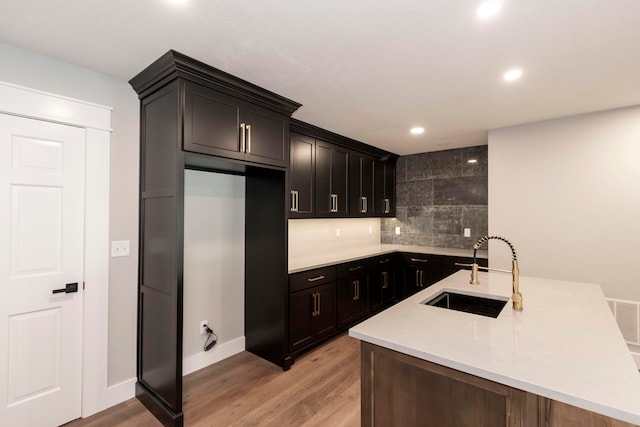 kitchen with light hardwood / wood-style floors, sink, and tasteful backsplash