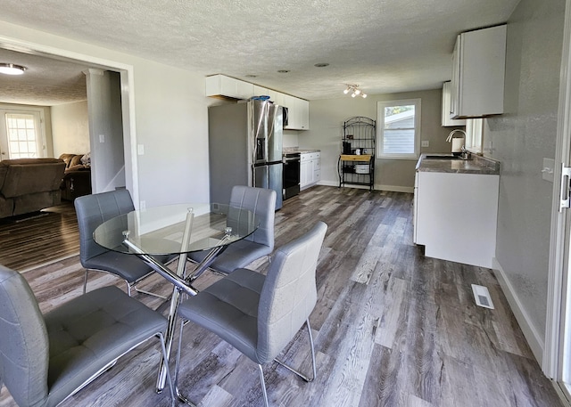 dining space featuring sink, wood-type flooring, and a textured ceiling