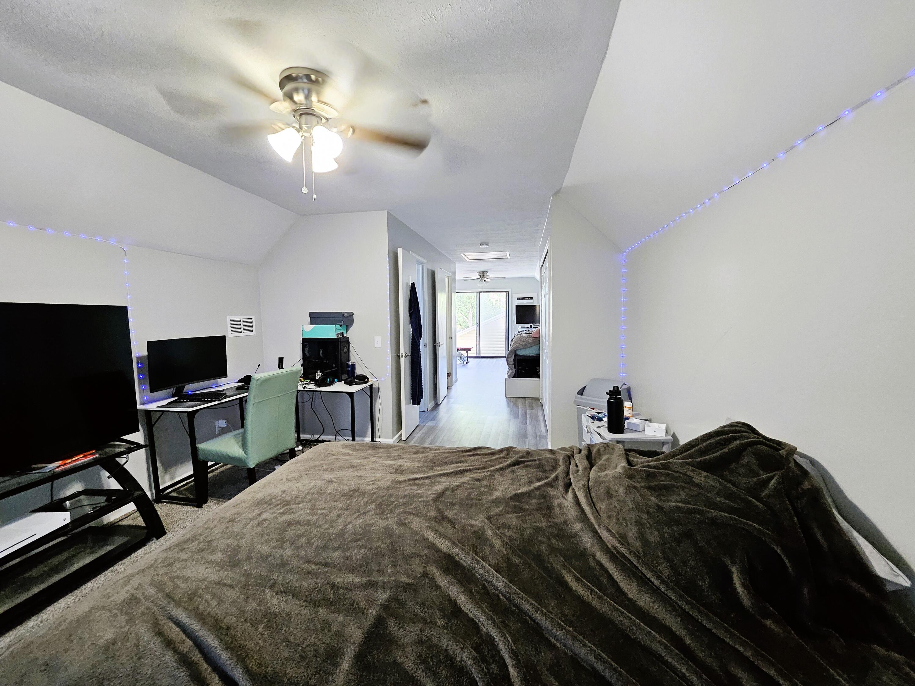 bedroom featuring vaulted ceiling, light hardwood / wood-style flooring, a textured ceiling, and ceiling fan