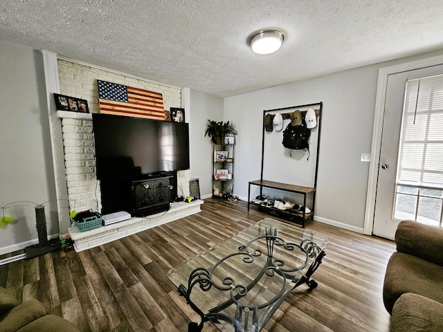 living room with wood-type flooring, a textured ceiling, and a wood stove