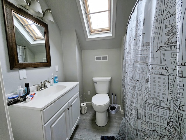 bathroom featuring tile patterned flooring, vaulted ceiling with skylight, toilet, a shower with shower curtain, and vanity