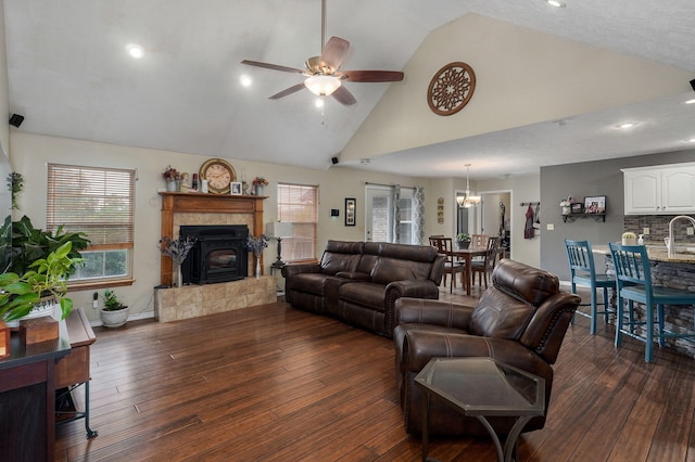 living room with high vaulted ceiling, ceiling fan, dark wood-type flooring, a fireplace, and a textured ceiling