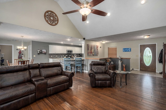 living room featuring wood-type flooring, a textured ceiling, ceiling fan with notable chandelier, and high vaulted ceiling