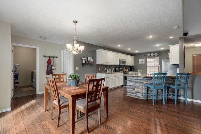 dining space with a notable chandelier, washer / clothes dryer, dark hardwood / wood-style flooring, and a textured ceiling