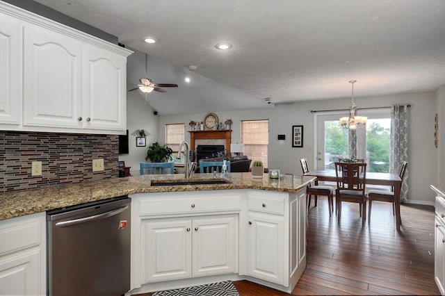 kitchen featuring lofted ceiling, hanging light fixtures, sink, stainless steel dishwasher, and white cabinetry