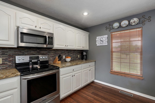 kitchen featuring stainless steel appliances, dark stone countertops, dark hardwood / wood-style flooring, and white cabinetry