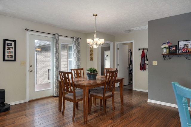 dining space featuring dark wood-type flooring, an inviting chandelier, and a textured ceiling