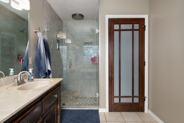 bathroom featuring tile patterned flooring, a shower with door, vanity, and a textured ceiling