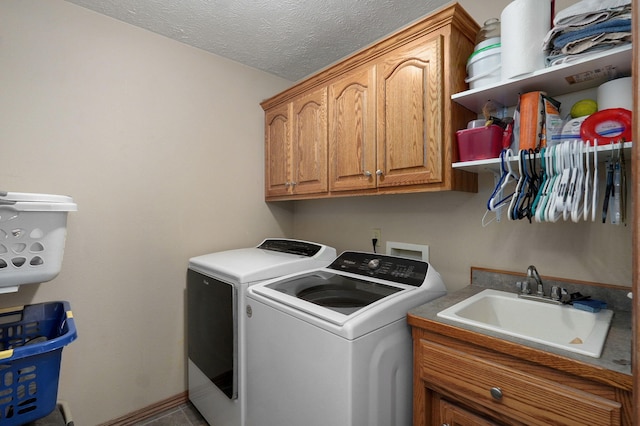 laundry room featuring a textured ceiling, independent washer and dryer, sink, and cabinets