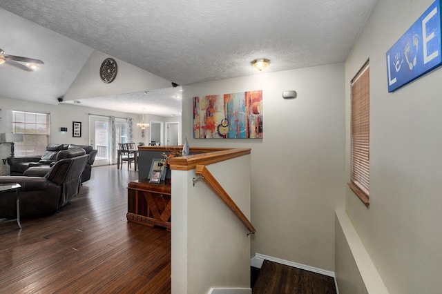 staircase featuring vaulted ceiling, a textured ceiling, ceiling fan with notable chandelier, and hardwood / wood-style floors