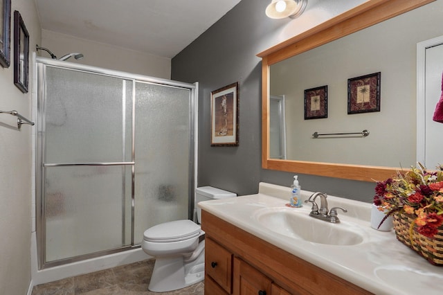 bathroom with vanity, a shower with door, and toilet