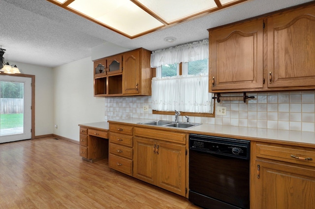 kitchen featuring light wood-type flooring, tasteful backsplash, black dishwasher, sink, and hanging light fixtures