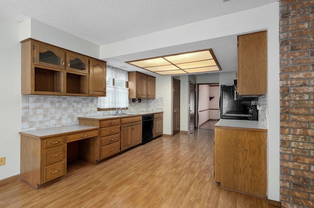 kitchen with sink, tasteful backsplash, a textured ceiling, light hardwood / wood-style flooring, and black appliances