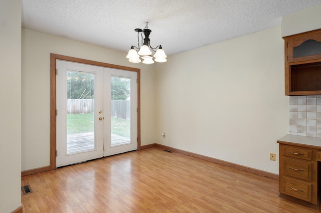 interior space featuring light wood-type flooring, an inviting chandelier, and a textured ceiling