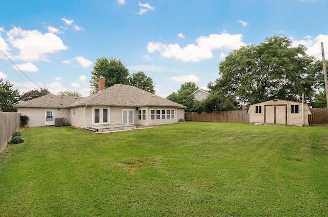 back of house with central AC unit, a storage unit, a patio, and a lawn