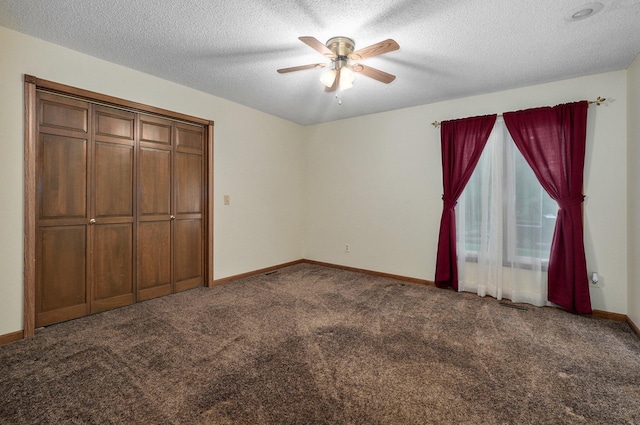 unfurnished bedroom featuring ceiling fan, a closet, dark carpet, and a textured ceiling