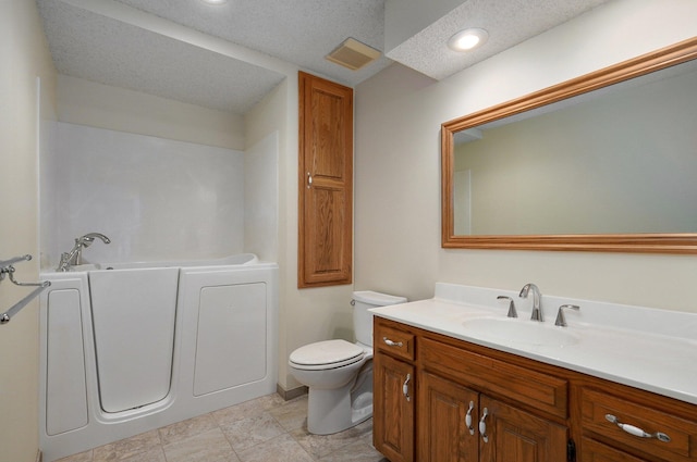 bathroom featuring toilet, a washtub, tile patterned floors, vanity, and a textured ceiling