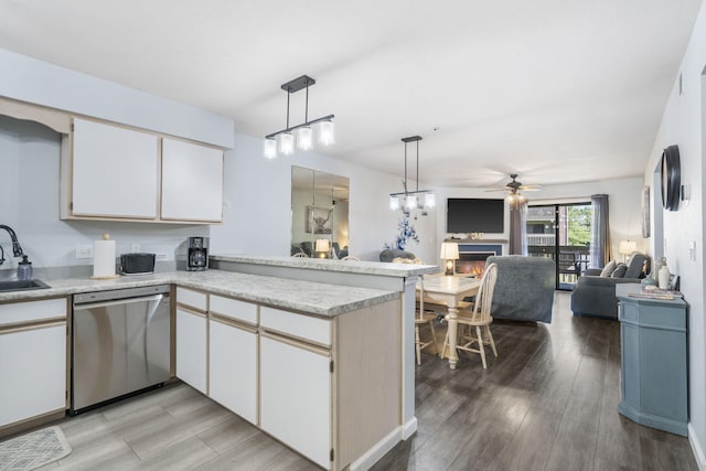 kitchen featuring pendant lighting, sink, kitchen peninsula, stainless steel dishwasher, and light hardwood / wood-style flooring