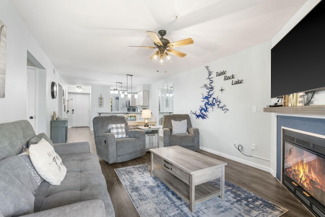 living room featuring ceiling fan with notable chandelier and dark wood-type flooring