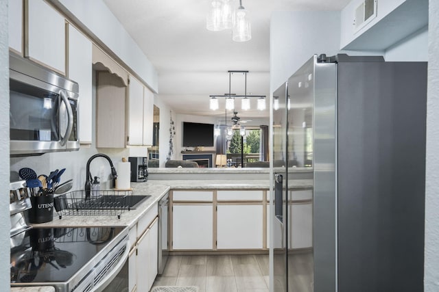 kitchen featuring ceiling fan, decorative light fixtures, stainless steel appliances, kitchen peninsula, and white cabinetry