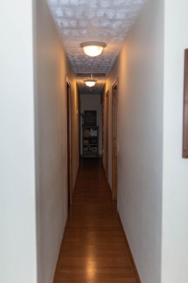 hallway with hardwood / wood-style floors and a textured ceiling