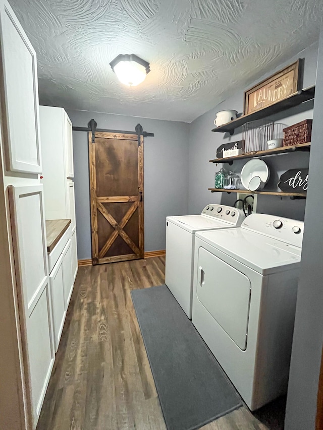 laundry room featuring dark hardwood / wood-style floors, a barn door, cabinets, washer and dryer, and a textured ceiling