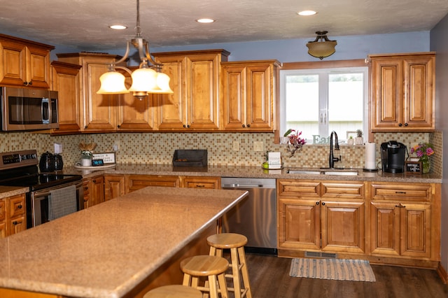 kitchen with sink, backsplash, appliances with stainless steel finishes, a breakfast bar, and dark hardwood / wood-style flooring