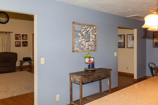 hall with a textured ceiling and dark hardwood / wood-style floors