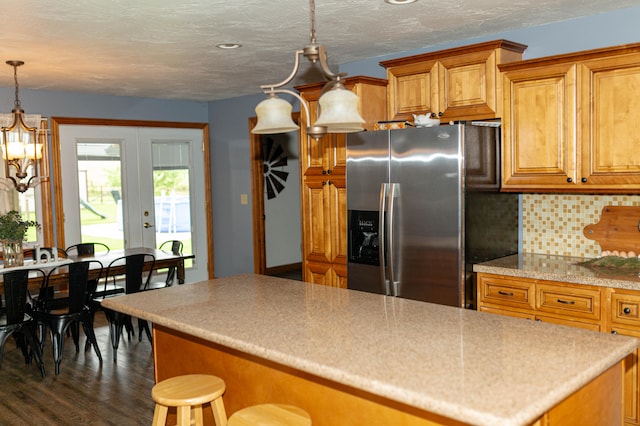 kitchen featuring french doors, dark hardwood / wood-style floors, stainless steel fridge, pendant lighting, and backsplash