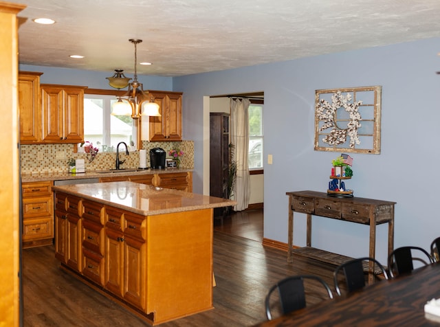 kitchen featuring a center island, tasteful backsplash, dark wood-type flooring, sink, and hanging light fixtures