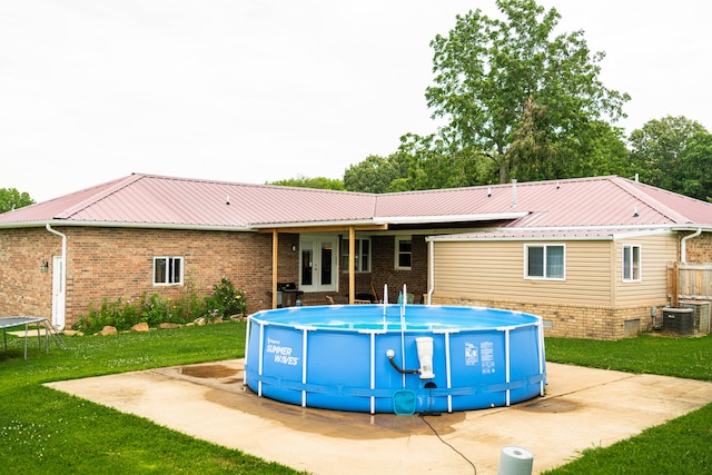 rear view of property with a yard and central air condition unit