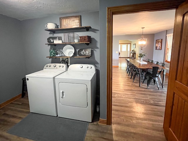 laundry area with hardwood / wood-style flooring, a notable chandelier, washing machine and clothes dryer, and a textured ceiling