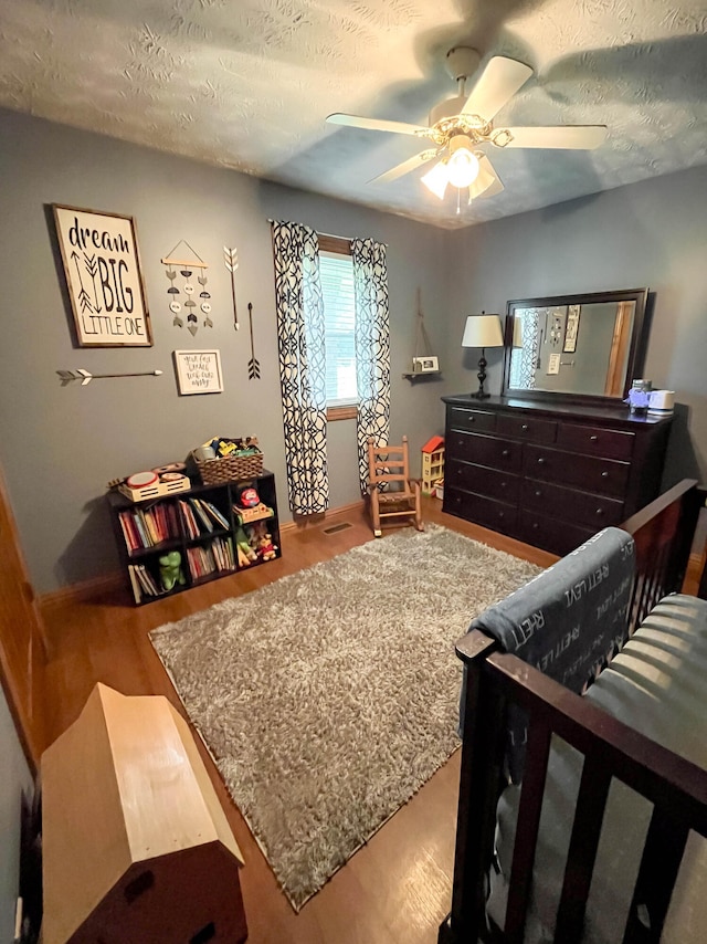 bedroom with wood-type flooring, a textured ceiling, and ceiling fan