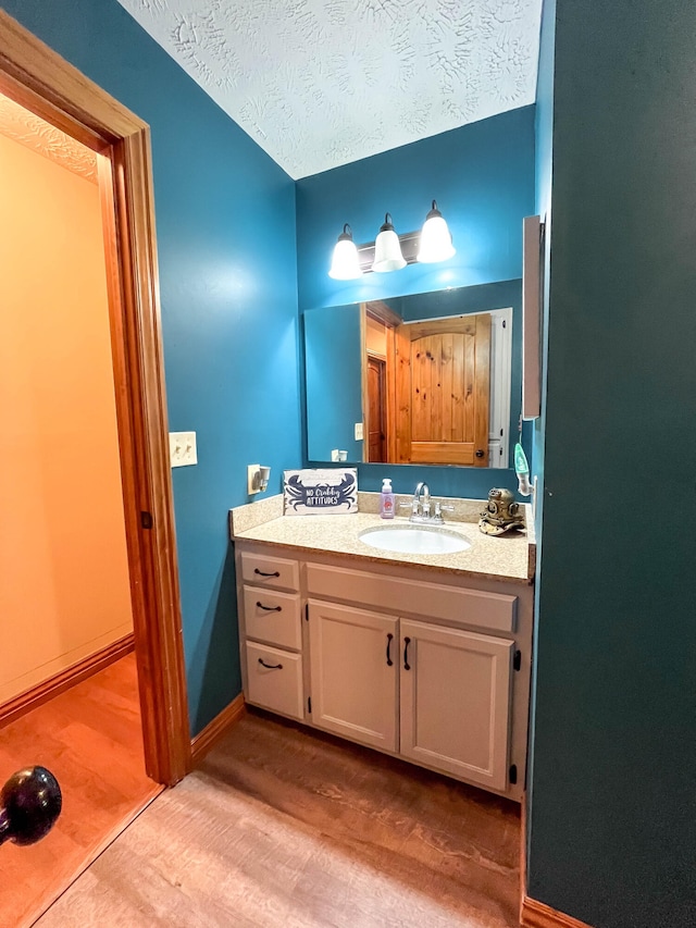 bathroom with hardwood / wood-style flooring, vanity, and a textured ceiling